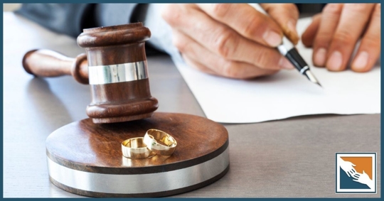 Judge gavel with wedding rings nearby and a man signing a divorce document